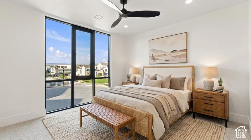 Expansive floor-to-ceiling windows with black framing, recessed ceiling lighting, textured carpet flooring, and a contemporary black ceiling fan
