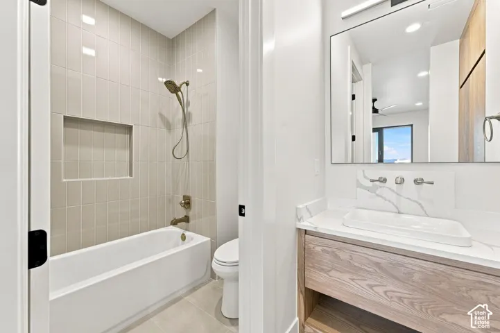 Bathroom featuring a built-in bathtub, a shower with a niche, a floating wood-finish vanity with a vessel sink, and a wall-mounted faucet