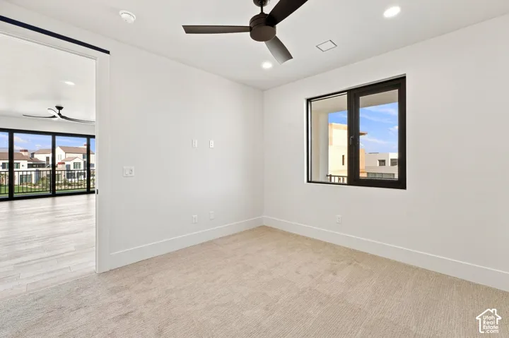 Recessed lighting, ceiling fan, white walls, dark-framed window, and neutral carpet