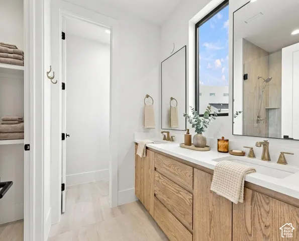 Double vanity with light wood-finish cabinetry, white countertop, and brass-finish fixtures