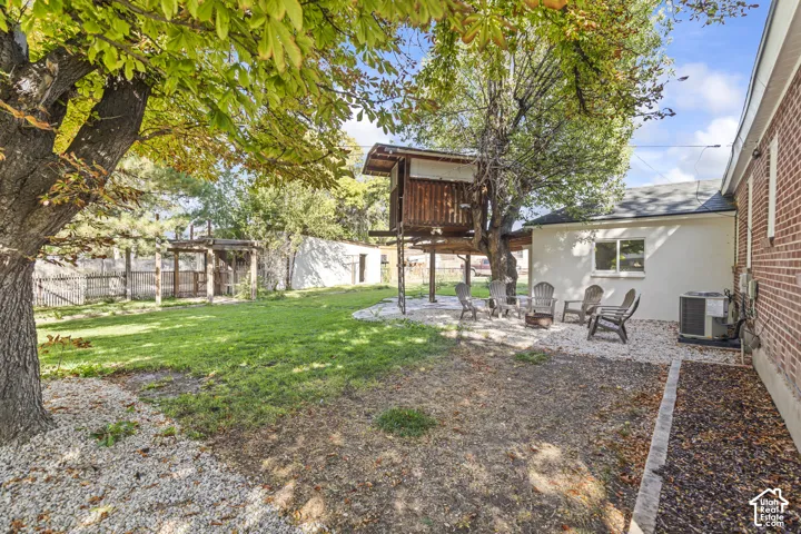 Expansive backyard featuring a manicured lawn, established shade trees, and a gravel patio area