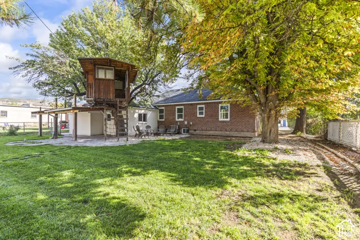 Expansive backyard with a manicured lawn, mature trees, and a treehouse with a covered patio