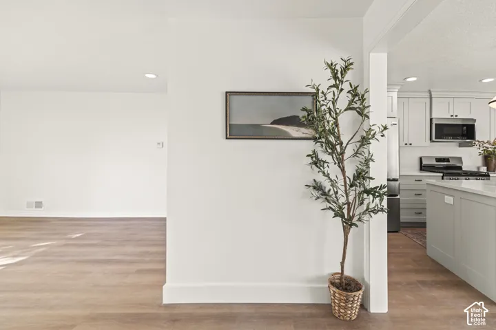 Wood-finish flooring, recessed lighting, and white wall finishes