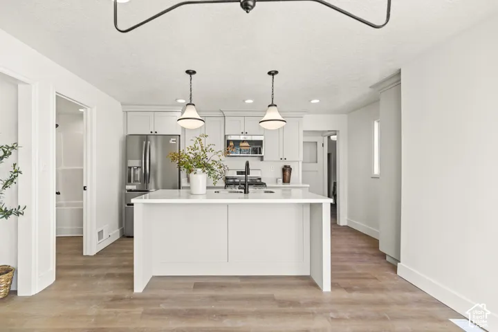 Kitchen featuring a central island, white cabinetry, stainless steel appliances, and a matte black faucet
