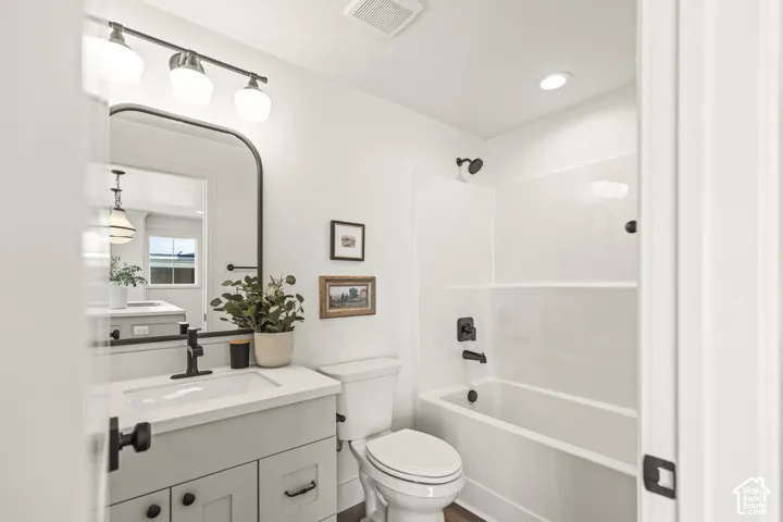 Bathroom featuring a white vanity with integrated sink, black hardware, arched mirror, and track lighting