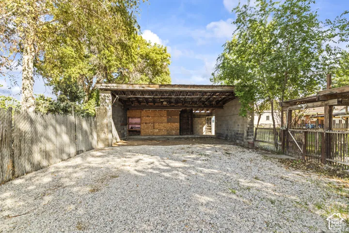Gravel parking area leading to a covered carport structure