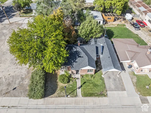 Single-story residence featuring a dark shingle roof and a front lawn with mature trees