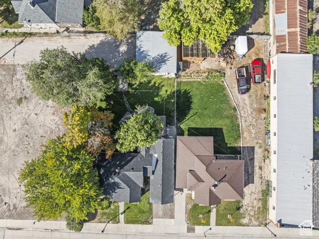 Property featuring two distinct buildings, green lawns, and mature trees, with a paved street frontage