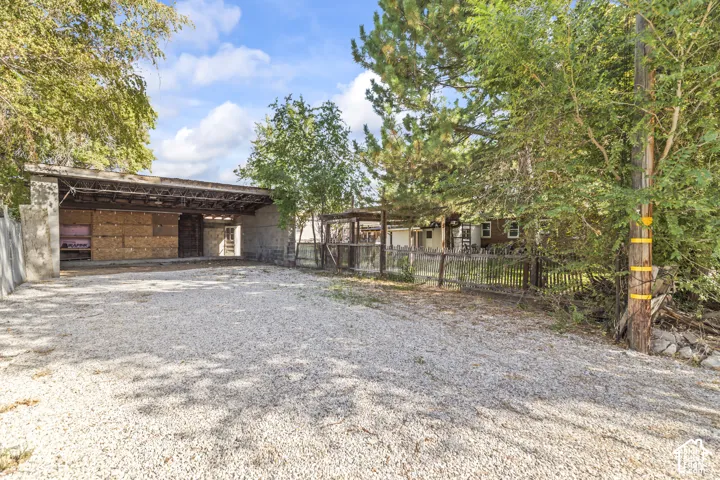 Gravel-paved surface with a covered shelter, surrounded by mature trees and natural landscaping