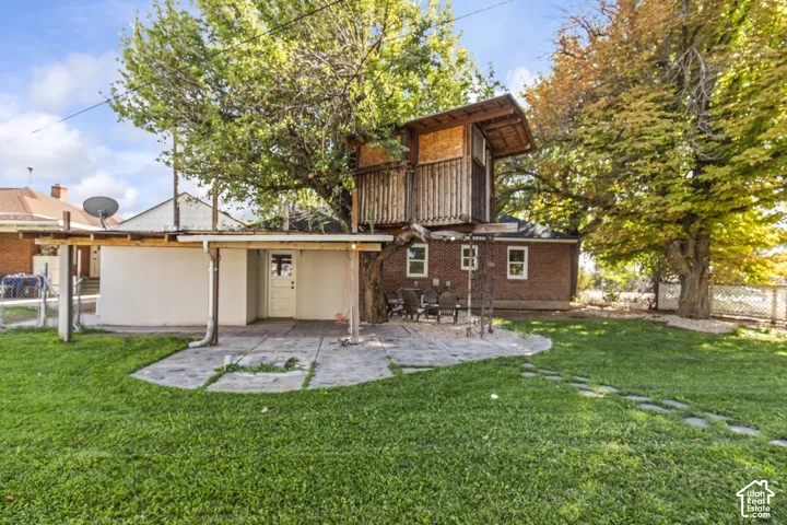 Expansive backyard featuring a green lawn, established trees, and a stone patio