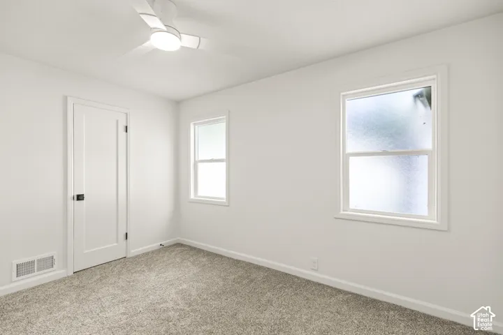 White walls, light gray carpet, and two windows with white trim