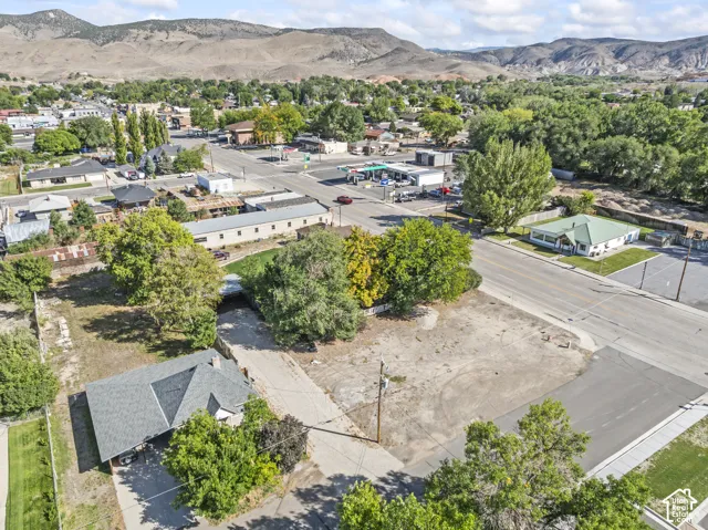 Aerial perspective of a property with an established building, surrounding structures, and a paved street
