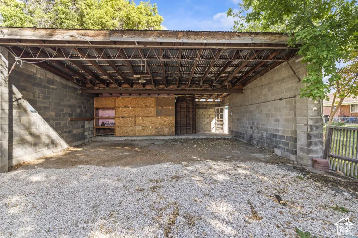 Covered structure with concrete block walls, exposed wood beam ceiling, and corrugated metal roofing