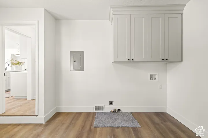 Built-in upper cabinetry with crown molding, wood-finish flooring, and white wall finishes