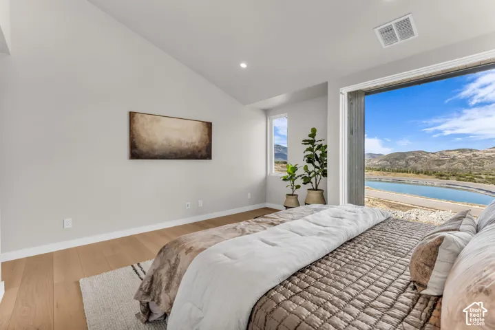 Vaulted ceiling, recessed lighting, wood-finish flooring, expansive sliding glass door, and large window