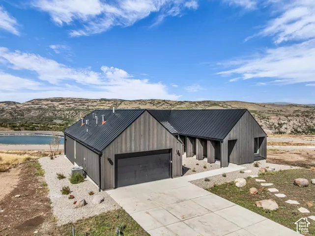 Contemporary exterior with vertical wood siding, a dark metal roof, concrete driveway, and natural rock landscaping