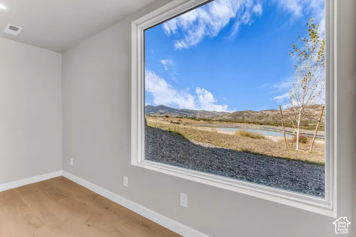 Large window framing a mountain backdrop and body of water, light-toned walls, recessed ceiling lighting, and wood-finish flooring