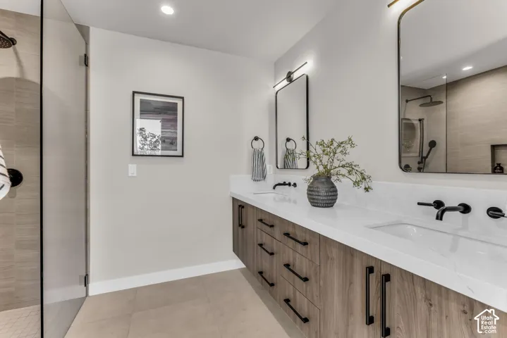 Dual vanity with wood-finish cabinetry, white countertops, and matte black fixtures