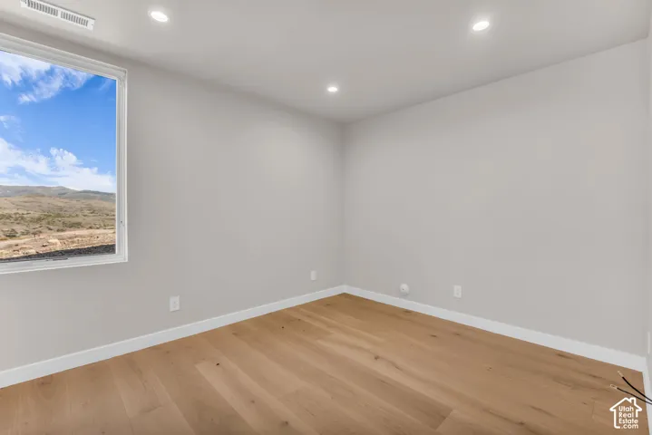Recessed lighting, wood-finish flooring, white trim, and a window with mountain scenery