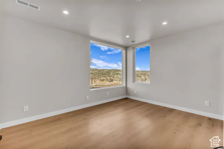 Recessed lighting, wood-finish flooring, white baseboards, and two windows providing expansive scenery