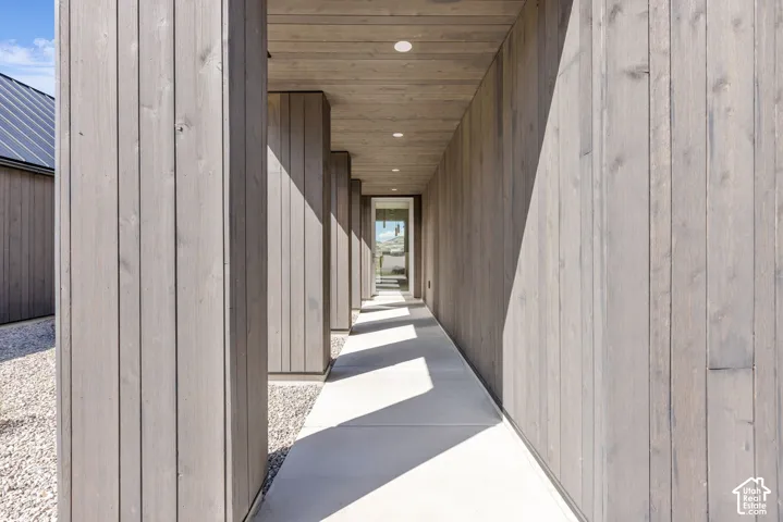 Exterior walkway with wood paneling, recessed lighting, and a gravel border