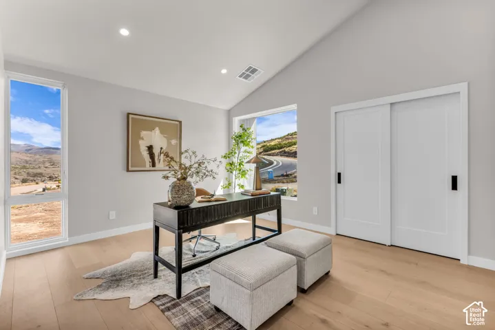 Vaulted ceilings with recessed lighting, light wood-finish flooring, white sliding closet doors with black hardware, and large windows with mountain scenery