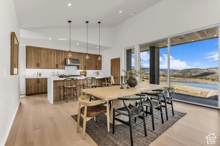 Open-concept kitchen and dining area featuring a vaulted ceiling and wood-finish flooring