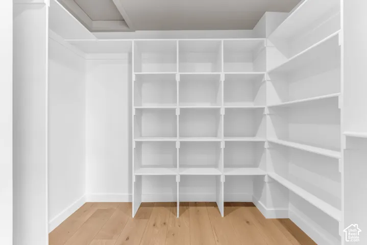Built-in white shelving system, ample storage, light wood-finish flooring