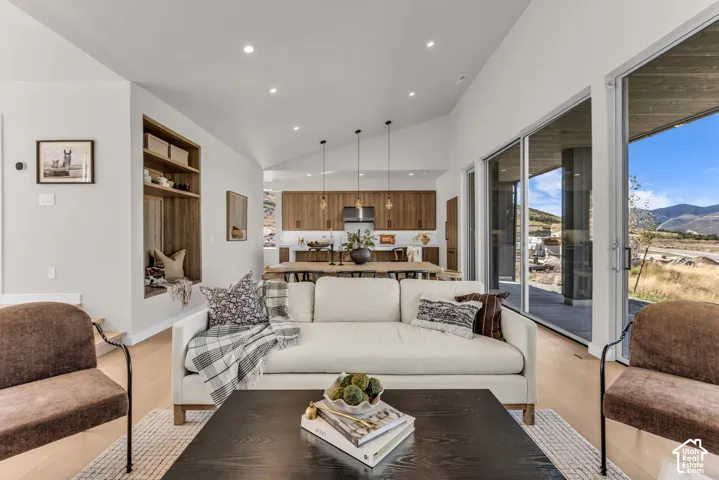 Vaulted ceiling with recessed lighting, light wood-finish flooring, built-in window seat with shelving, and large sliding glass doors