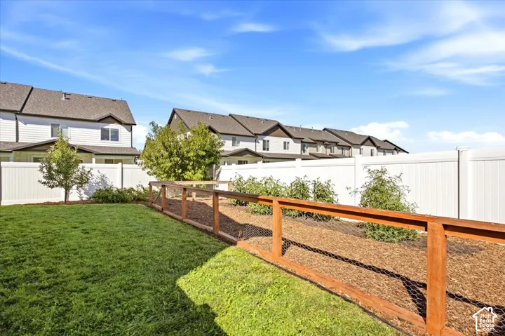 Manicured lawn with a white privacy fence and wood-frame garden area