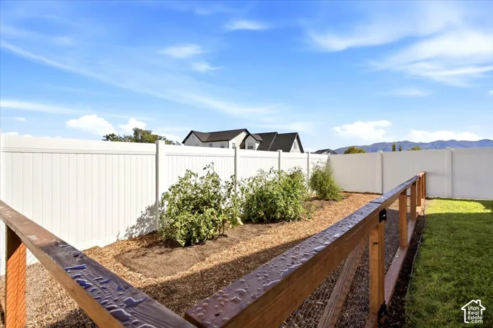 Expansive backyard featuring a manicured lawn, a garden bed with plantings, and a privacy fence