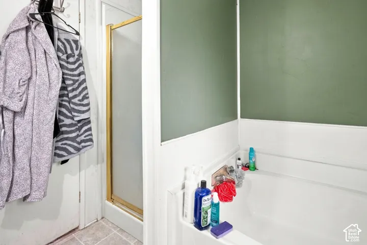 Bathtub with a shower combination, featuring a gold-finish frame and a light green wall finish
