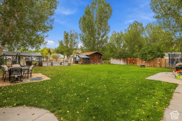 Expansive backyard with a manicured lawn, paved patio, and mature trees