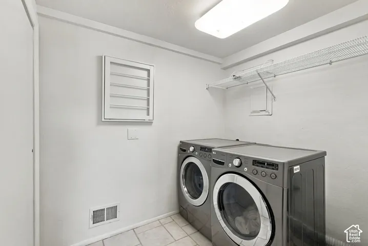 Laundry area featuring tile flooring, wall-mounted drying rack, and wire shelving