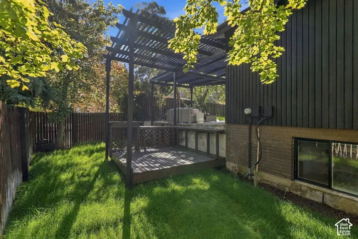 Private backyard featuring a wood deck and pergola, vertical siding, and a fenced perimeter