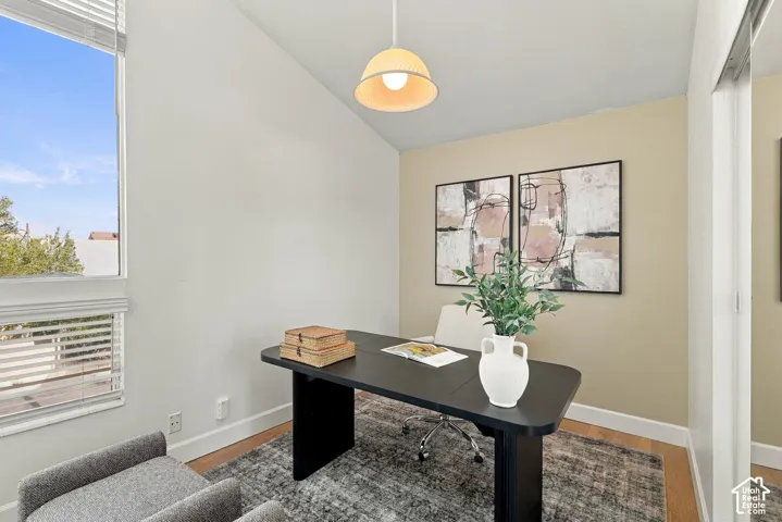 Sloped ceiling, recessed lighting, wood-finish flooring, large window with blinds, and white trim
