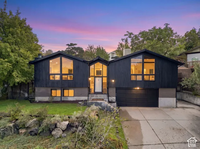 Split-level architecture featuring black vertical siding and a lower brick facade