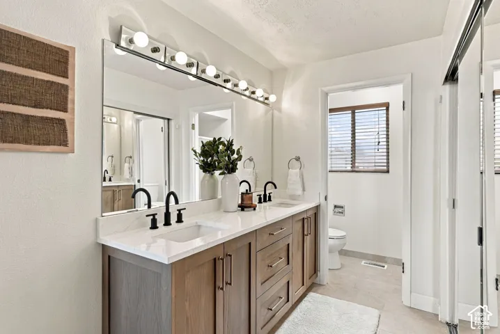 Dual vanity with wood-finish cabinetry, white countertop, and matte black hardware