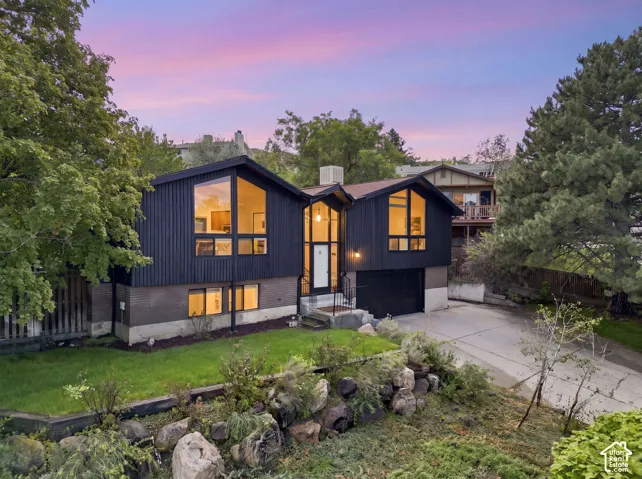 Split-level residence featuring dark vertical siding and a gable roof