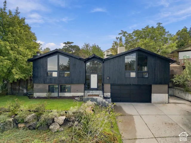 Contemporary exterior with dark vertical siding, prominent triangular windows, and an integrated two-car garage