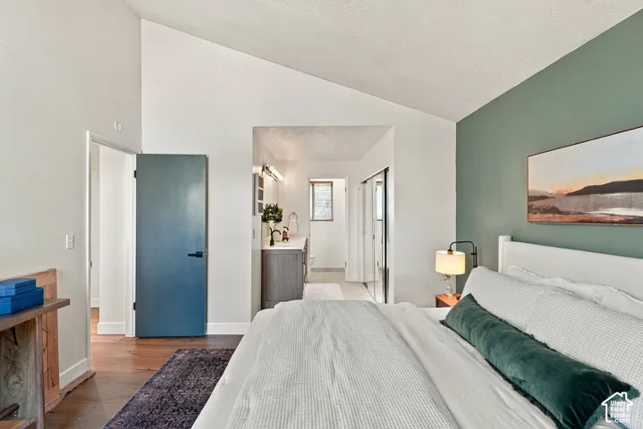 Room featuring a vaulted ceiling, wood-finish flooring, and a contrasting accent wall