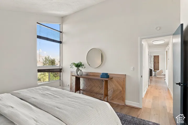 Vaulted ceiling, large window with blinds, wood-finish flooring, recessed lighting, and a modern ceiling light fixture
