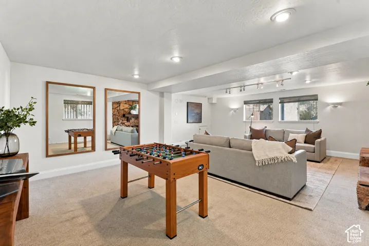 Recessed lighting, track lighting, and wall sconces illuminate this carpeted room featuring multiple windows