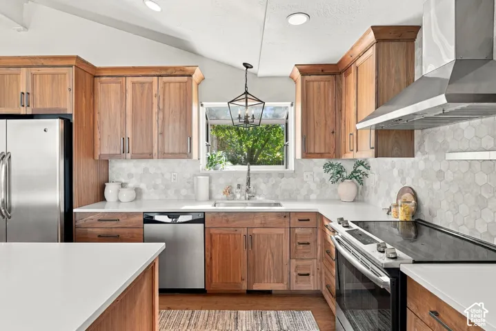 U-shaped kitchen featuring wood cabinetry, white countertops, hexagonal tile backsplash, and stainless steel appliances