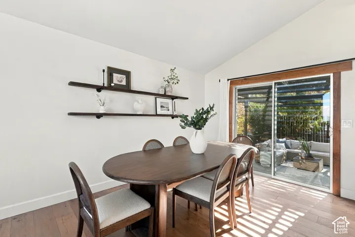 Vaulted ceiling, wood-finish flooring, built-in shelving, sliding glass door, and a patio with a pergola