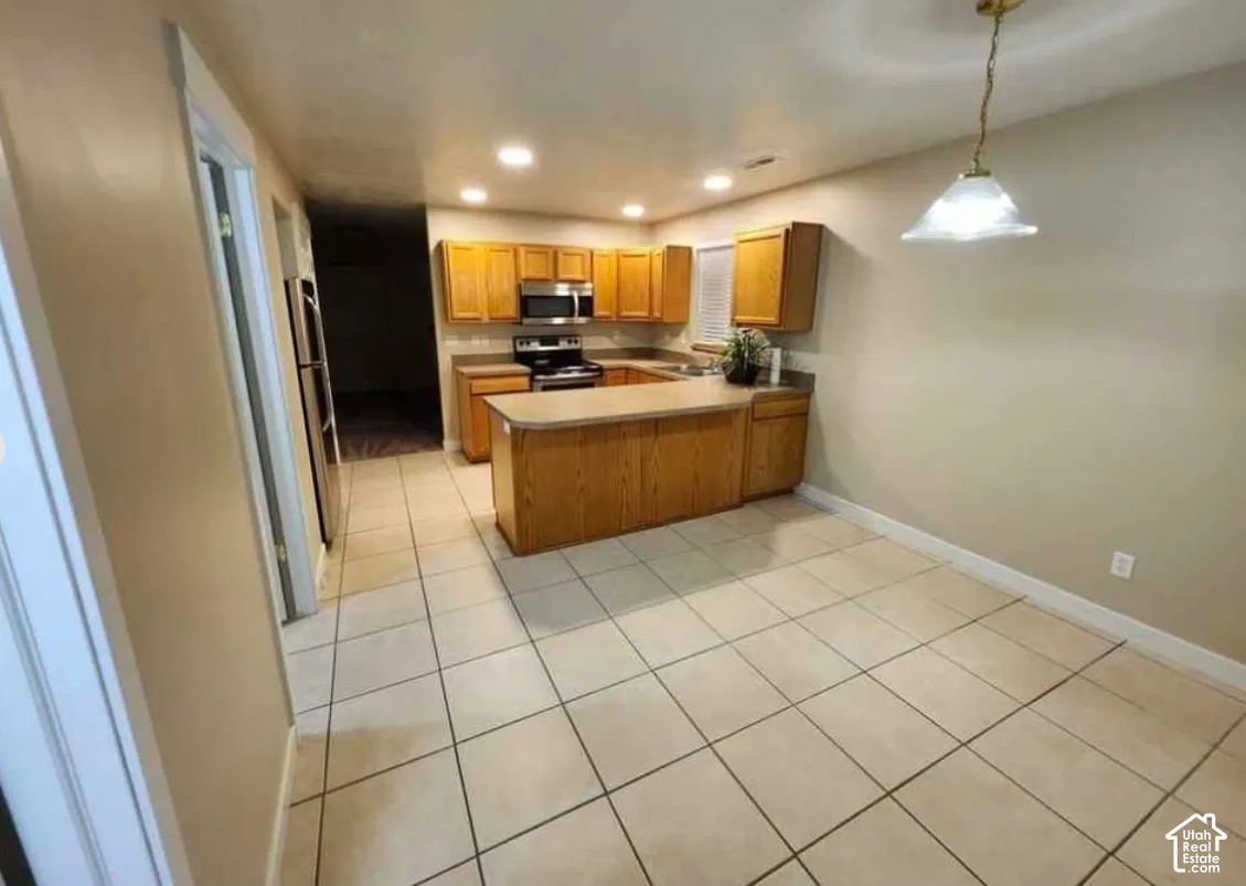 Kitchen featuring wood-finish cabinetry, stainless steel appliances, and a central island with countertop seating