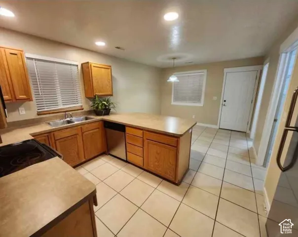 Kitchen featuring warm wood-finish cabinetry, neutral countertops, stainless steel sink, and recessed lighting