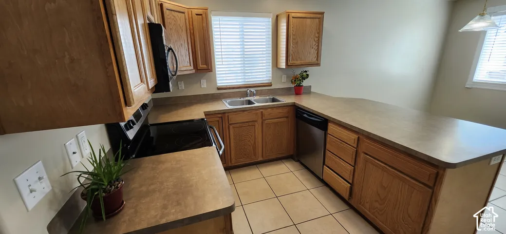 U-shaped kitchen featuring wood cabinetry, integrated stainless steel dishwasher, double basin sink, and ample countertop space