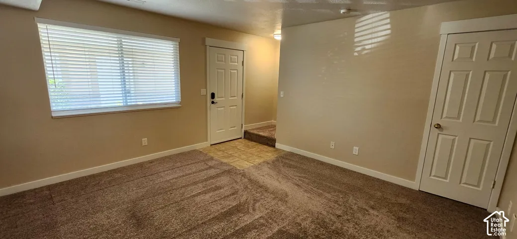 Neutral wall paint, window with blinds, carpet flooring, paneled door, and tiled entry