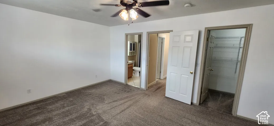 Carpeted room featuring a ceiling fan with integrated lighting, a panel door, and a built-in closet with wire shelving